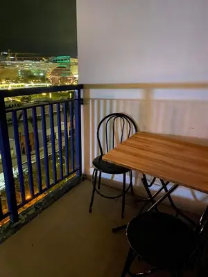 a table and chairs on a balcony with a view of a city at Azenith Staycation At Sea Residences Moa in Manila