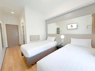 two beds in a room with white walls and wood floors at Red Planet Ortigas in Manila