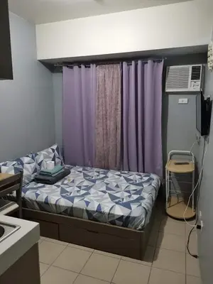 a small bedroom with a bed and purple curtains at Mack's Awesome Place 11 with Netflix and FastUnliwifi in Manila
