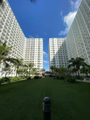 two large white buildings with palm trees in a park at Cozy Space at Shore Residences in Tower D in Manila