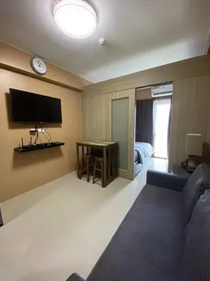 a living room with a couch and a tv on the wall at Cozy Space at Shore Residences in Tower D in Manila