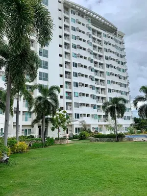 a large building with palm trees in front of a park at At Home Condo With Free Pool Access in Manila