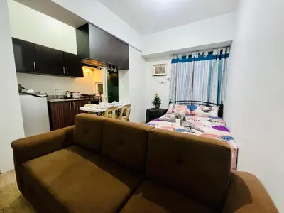 a living room with a couch and a kitchen at At Home Condo With Free Pool Access in Manila