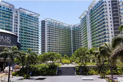 a large building with palm trees in front of it at AZURE URBAN RESORT - PARANAQUE MANILA NEAR TERMINAL UNLIMITED WIFI and Netflix in Manila