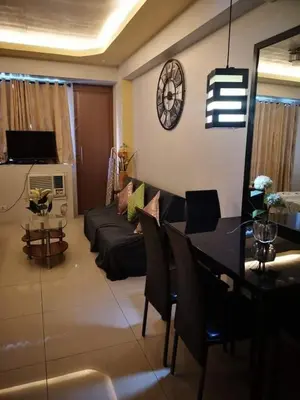 a living room with a couch and a table and a clock at One Palm Tree Villas NAIA TERMINAL 3 in Manila