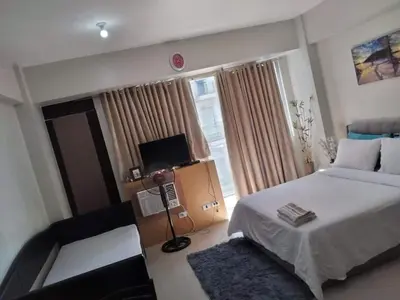 a bedroom with a bed and a chair and a television at One Palm Tree Villas NAIA TERMINAL 3 in Manila