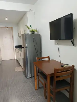 a kitchen with a table and a tv and a refrigerator at Sea Residences TowerE-F by EZStays in Manila