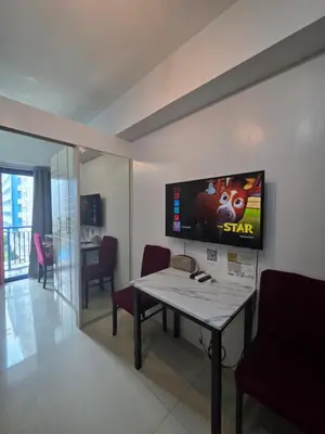 a living room with a table and a tv on the wall at Sea Residences TowerE-F by EZStays in Manila