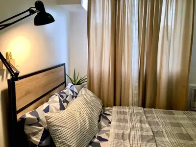 a bedroom with a bed with a lamp and curtains at Pacific Residences Condo Del Juana Near BGC Taguig in Manila