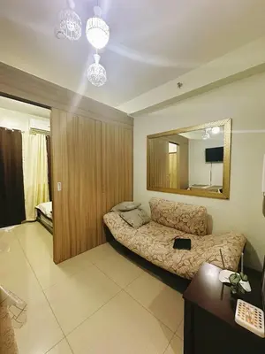a bedroom with a couch and a large mirror at Adel's Cosy Place - SMDC Shore 2 Philippines in Manila