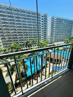 a balcony with a pool and a large building at Shell Residence MOA Manila by JO Alano in Manila