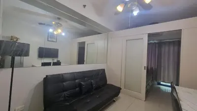 a living room with a black leather couch and a mirror at Sea Residences EZBedz in Manila
