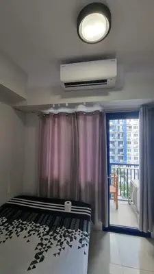 a bedroom with a bed and a window with a balcony at Sea Residences EZBedz in Manila