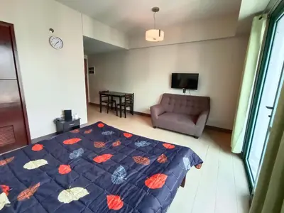 a bedroom with a bed and a couch and a tv at Palm Tree Two Villas in Manila