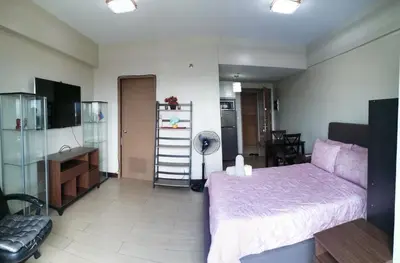 a bedroom with a large bed and a kitchen at Palm Tree Two Villas in Manila