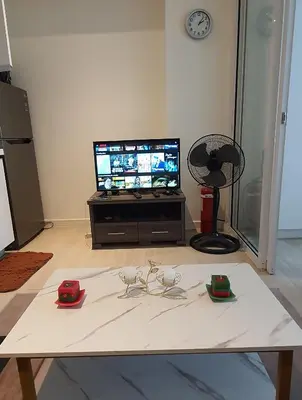 a living room with a table with glasses and a tv at JN Condotel The Azure Urban Resort Residences in Manila