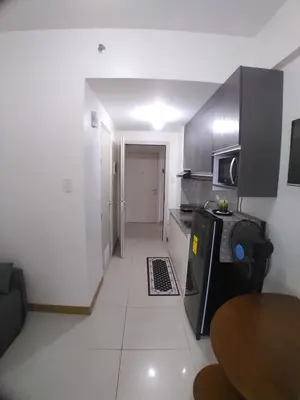 a small kitchen with a table and a microwave at SM South Residences, 1 bedroom with balcony. in Manila