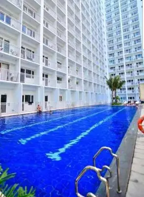 a large swimming pool in front of a large building at Chic Nordic Condo Unit at Shore Residences Mall of Asia in Manila