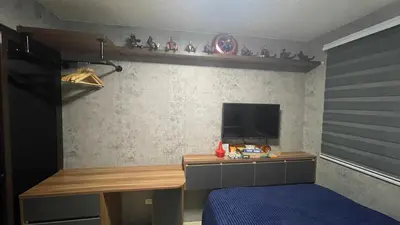 a bedroom with a bed and a desk with a tv at Marvel Suite Staycation -Near Doña Elena Tower in Manila