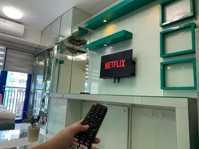 a person holding a remote control in front of a television at Sea Residences in Manila