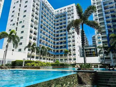 a large building with palm trees and a swimming pool at Sea Residences in Manila