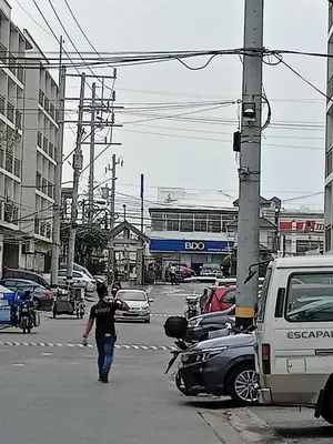 a man walking across a city street with cars at KASELDORZHOSTEL TRANSIENT at Moonwalk Paranaque in Manila