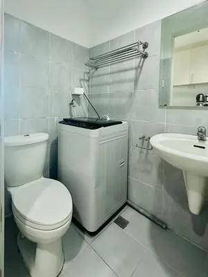 a white bathroom with a toilet and a sink at Sea Residences in Manila