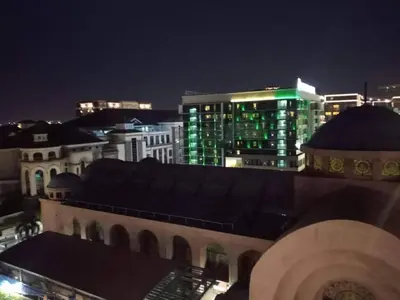 a city skyline at night with a green building at Budget Apartment Manila across Manila Airport T3 in Manila