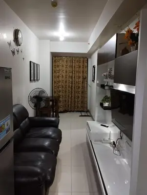 a living room with a leather couch and a kitchen at Sea Residences MOA by JO Alano New in Manila