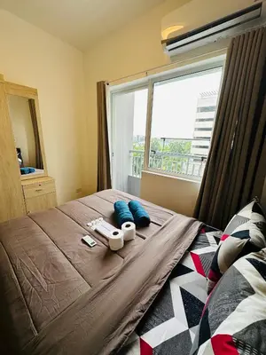 a bedroom with a bed with blue pillows and a window at Grace Residences 1 Bedroom With Balcony Bgc View Netflix in Manila