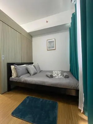 a bedroom with a large bed with green curtains at Grace Residences 1 Bedroom With Balcony Bgc View Netflix in Manila