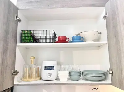 a kitchen cabinet filled with bowls and utensils at 1BR Suite near Megamall, Boni & Shaw MRT Station in Manila