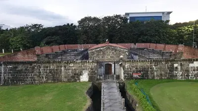 an old brick building with a gate in a field at MANILA BAY FRONT DELUX Pearl of the orient in Manila