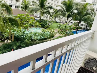a balcony of a resort with a pool and palm trees at Shore Residence D1,shortwalk MALL OF ASIA near airport wifi in Manila