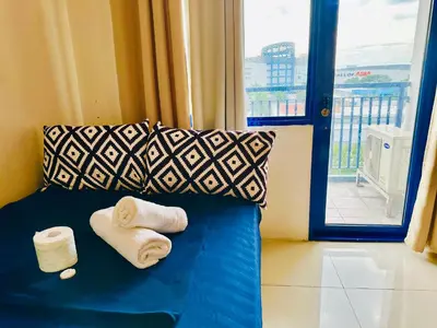 a blue bed with towels and pillows and a window at Sea Residences - Property Val Alano 0995-448-8872 in Manila