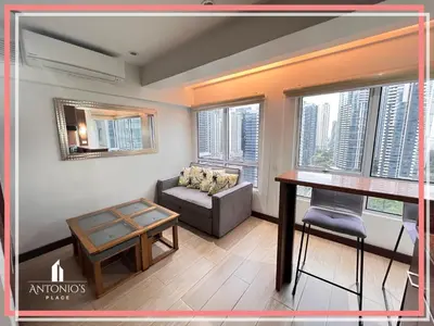 a living room with a table and a couch at Panoramic View of City 1BR Loft Unit FREE WIFI & NETFLIX at Fort Victoria BGC in Manila