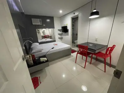 a bedroom with a bed and a desk with a red chair at Hotel Sogo Edsa Cubao in Manila