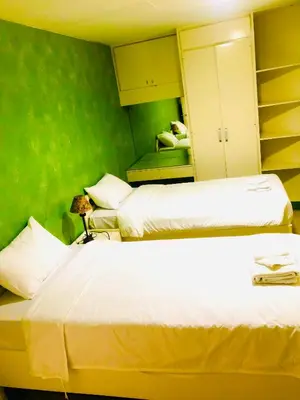 two beds in a room with green walls at Benson Hotel San Juan CIty in Manila