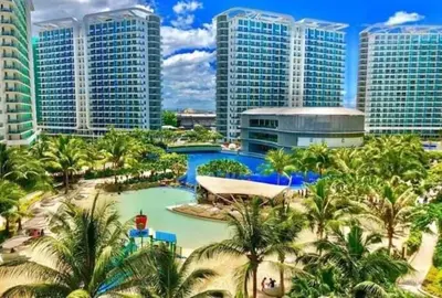 a resort with a pool with palm trees and buildings at S-A-F-E Haven Resort Staycation in Manila
