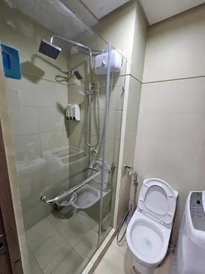 a bathroom with a toilet and a glass shower at Mel and Rose Place in S Residences Tower 1 MOA in Manila