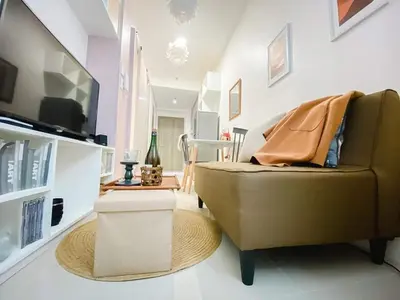 a living room with a couch and a television at Fame Residences Tower-1 Unit 3207 in Mandaluyong 1 Br w Balcony City view in Manila
