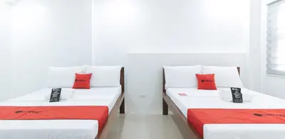 two beds in a room with white and red pillows at RedDoorz Plus at DBuilders Poblacion BGC in Manila
