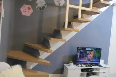 a room with a staircase with a tv and a shelf at A2J BGC Luxury 2BR Loft Near Burgos Circle, Malls in Manila
