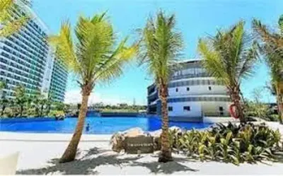 a group of palm trees in front of a building at AZURE A6 beachpool with Balcony Wifi near mall airport in Manila