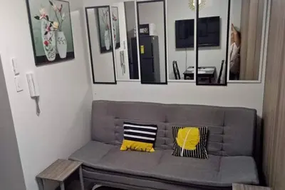 a living room with a gray couch and mirrors at MOA Shore 2 1BR with Balcony WiFi Netflix Pool 4Pax in Manila