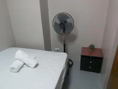 a bedroom with a bed with a fan and a table at Affordable Tagaytay Monteluce 2 BR Loft with pool 32 in Lalaan Primero