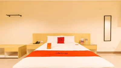 a bedroom with a bed with a red pillow on it at RedDoorz Plus @ Kaizen Suites Taft Avenue in Manila