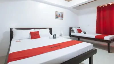 a bedroom with two beds and a red curtain at RedDoorz near UST Sampaloc Manila in Manila