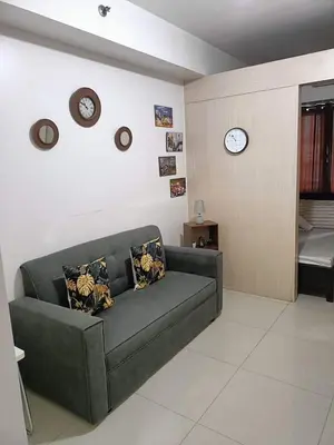 a living room with a couch and clocks on the wall at Blue's Residences in Manila