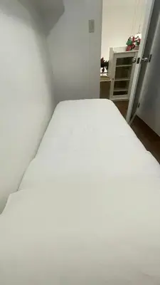 a bed in a small room with a white bedsheet at Modern Condotel Stay with Netflix, Kitchen & Washer, Near MRT Boni in Manila